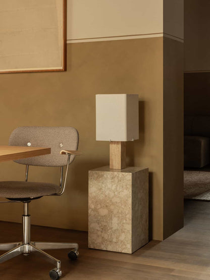 The Nonna Table Lamp on a Plinth Tall illuminates an office corner, with a grey Co Task Chair pulled up to a wooden desk.