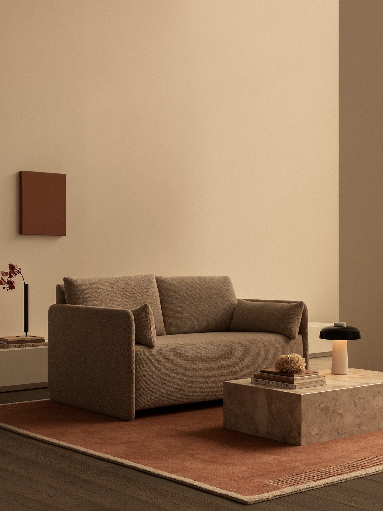 A brown Offset Sofa Bed in a minimal room, on a rust Duomo Rug with a marble Plinth Low table and Reverse Table Lamp.