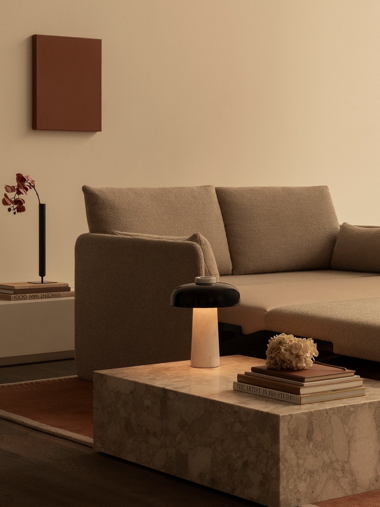 A beige Offset Sofa Bed in a living room with a marble Plinth Low table, Reverse Table Lamp, and rust-coloured Duomo Rug.