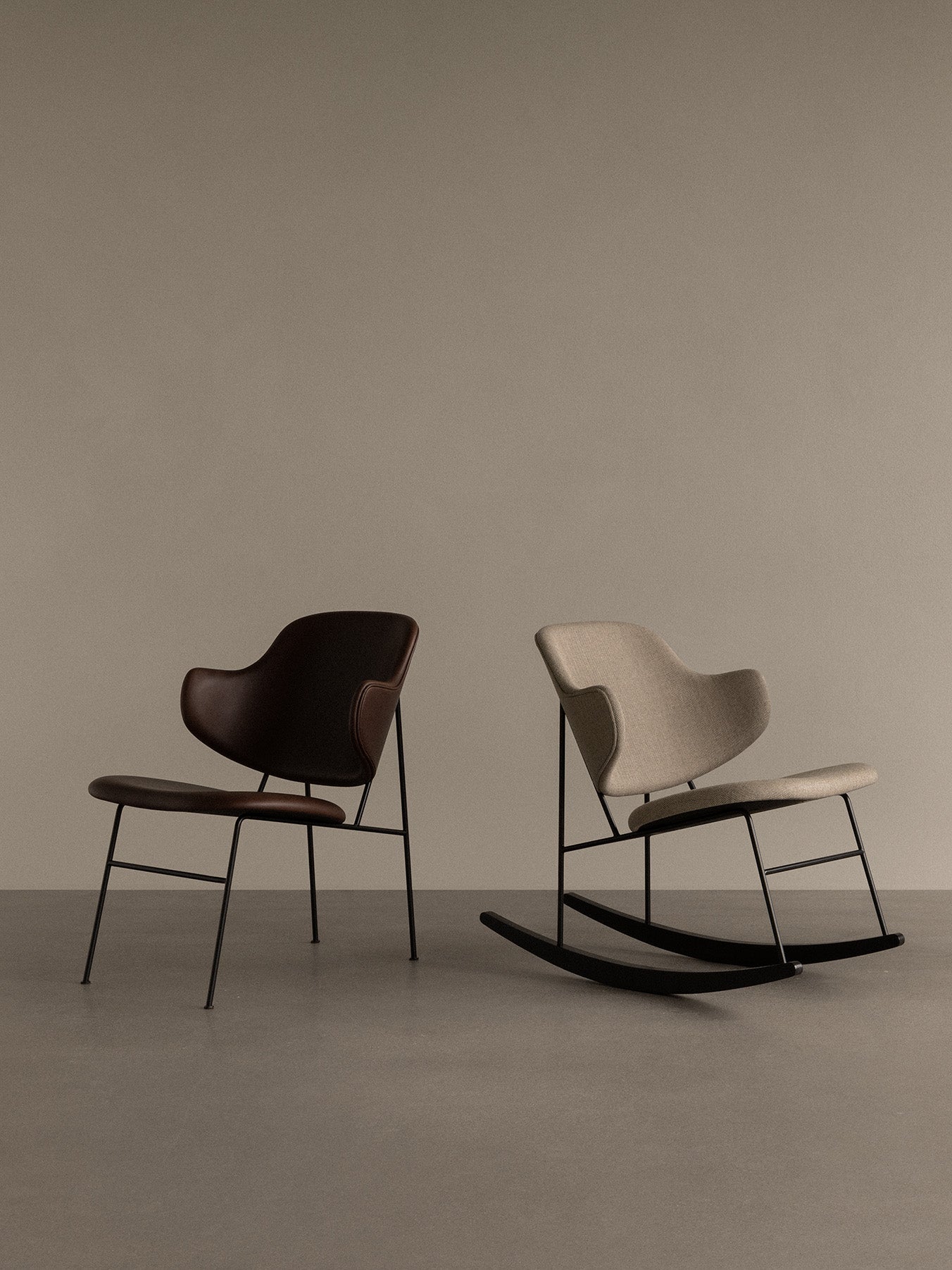 A light fabric Penguin Rocking Chair and a dark leather Penguin dining chair with black metal frames in a minimalist setting.