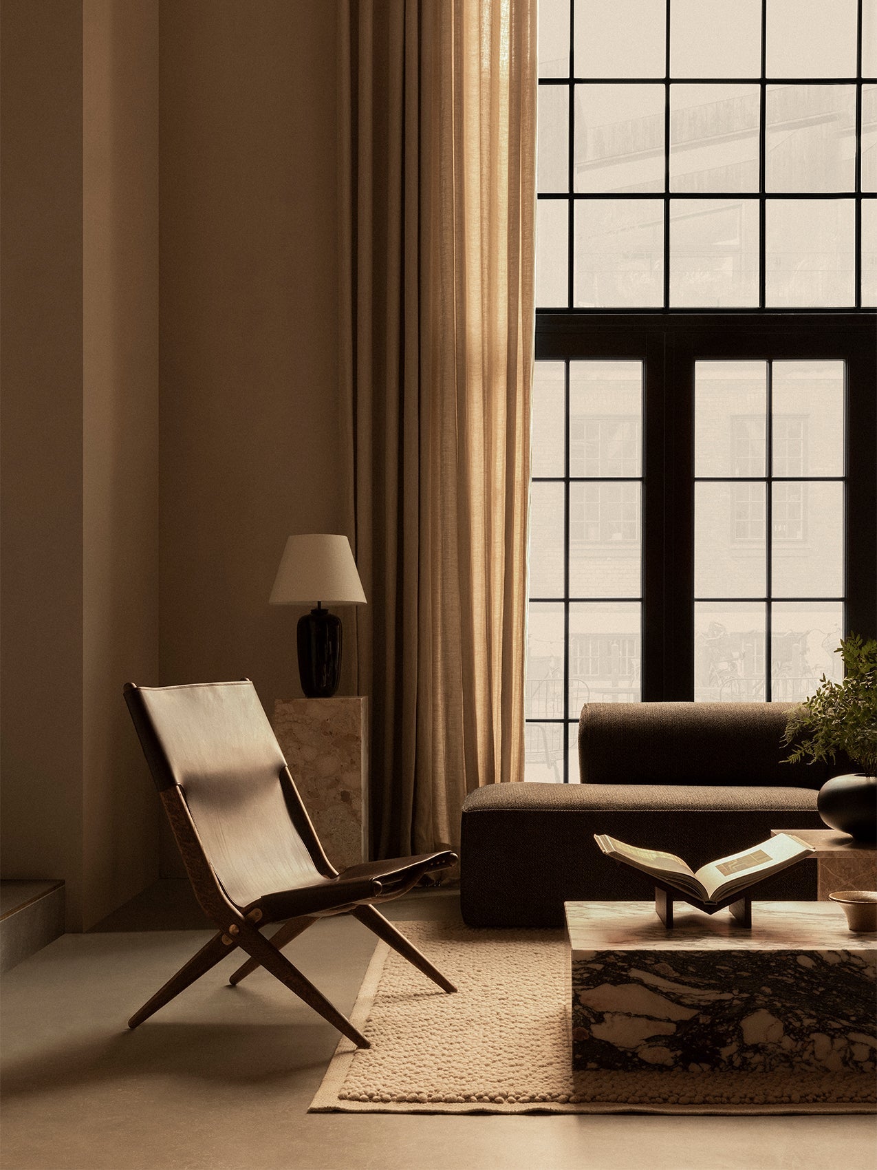 living room setting with a leather Saxe Chair, an Eave Modular Sofa, Plinth marble tables and a Torso lamp by a large window