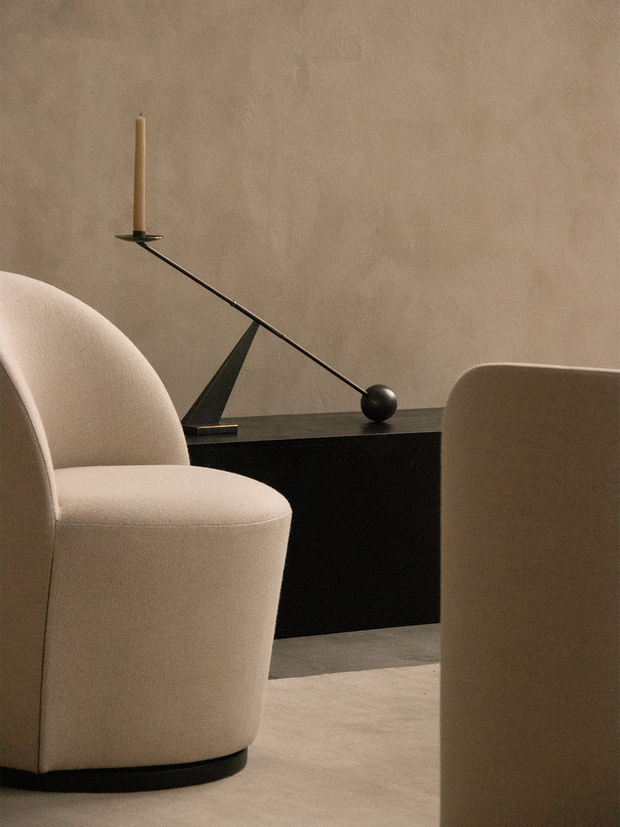 Close-up of the cream Tearoom Club Chair with swivel base, with the black Interconnect Candle Holder on a console behind it.