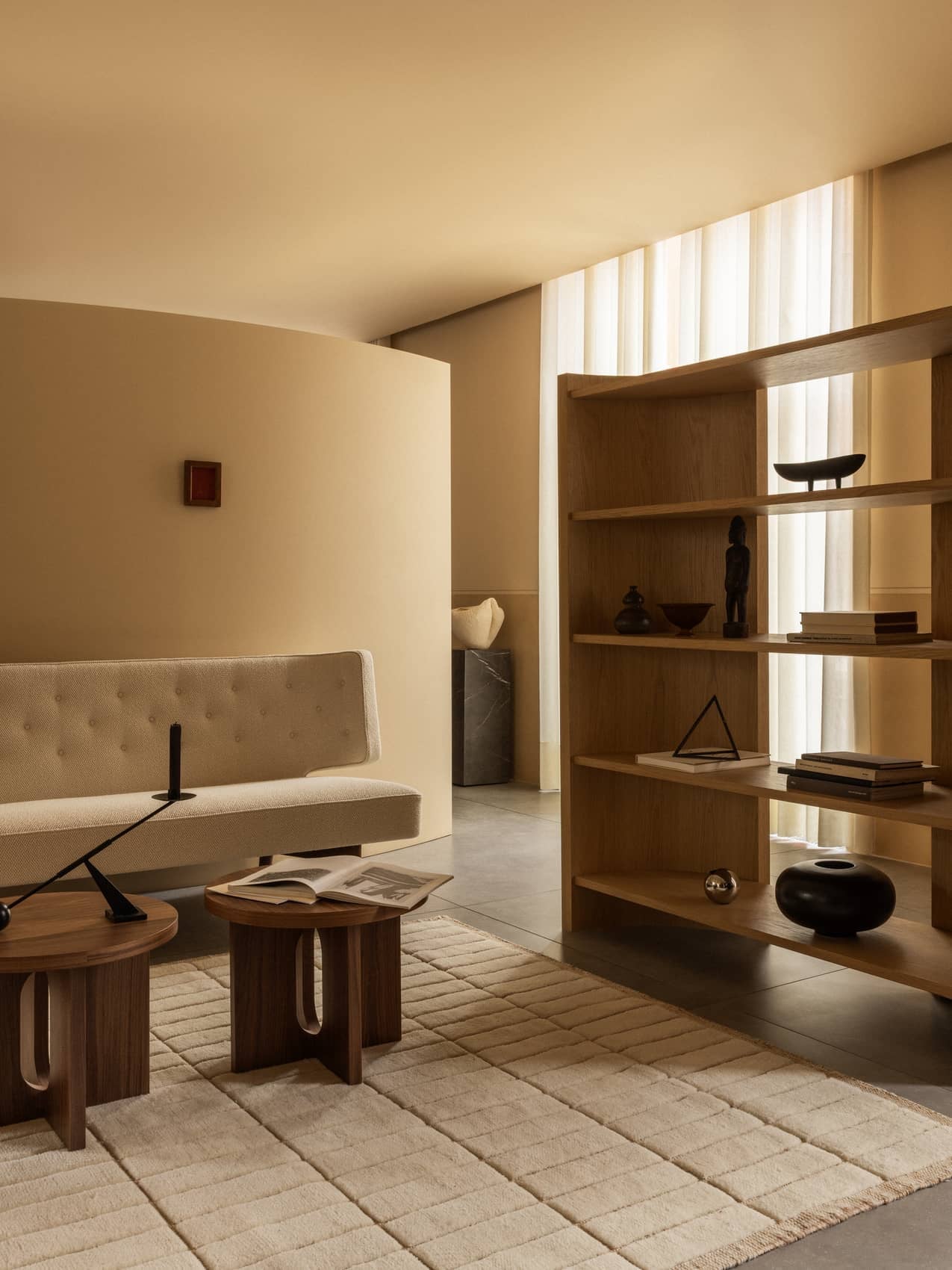 A living room with a Radiohus Sofa, Androgyne Side Tables with an Interconnect lamp, a Tile Rug, and Crescent Shelving.