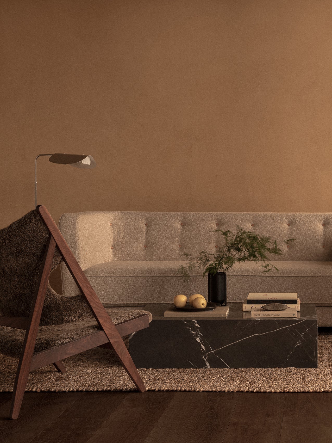 A Vilhelm Sofa in a warm-toned living room with a Saxe Lounge Chair, a black marble Plinth, and a Wing Floor Lamp.
