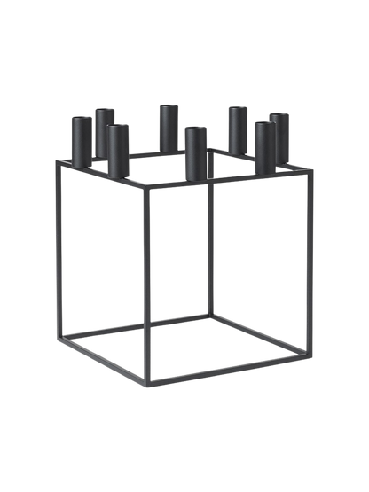 The black metal Kubus 8 candle holder, a minimalist cube frame with eight cylindrical holders for candles.