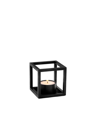 The Kubus T candle holder in black, a cube-shaped frame holding a single lit black tealight against a plain white background.