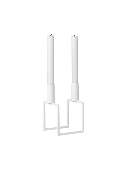 An angled view of the white Kubus Line candlestick, a minimalist design with a geometric frame, holding two white candles.