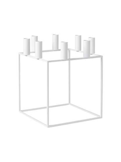 The white Kubus 8 candle holder, a minimalist cube-shaped frame with holders for eight candles, viewed from an angle.