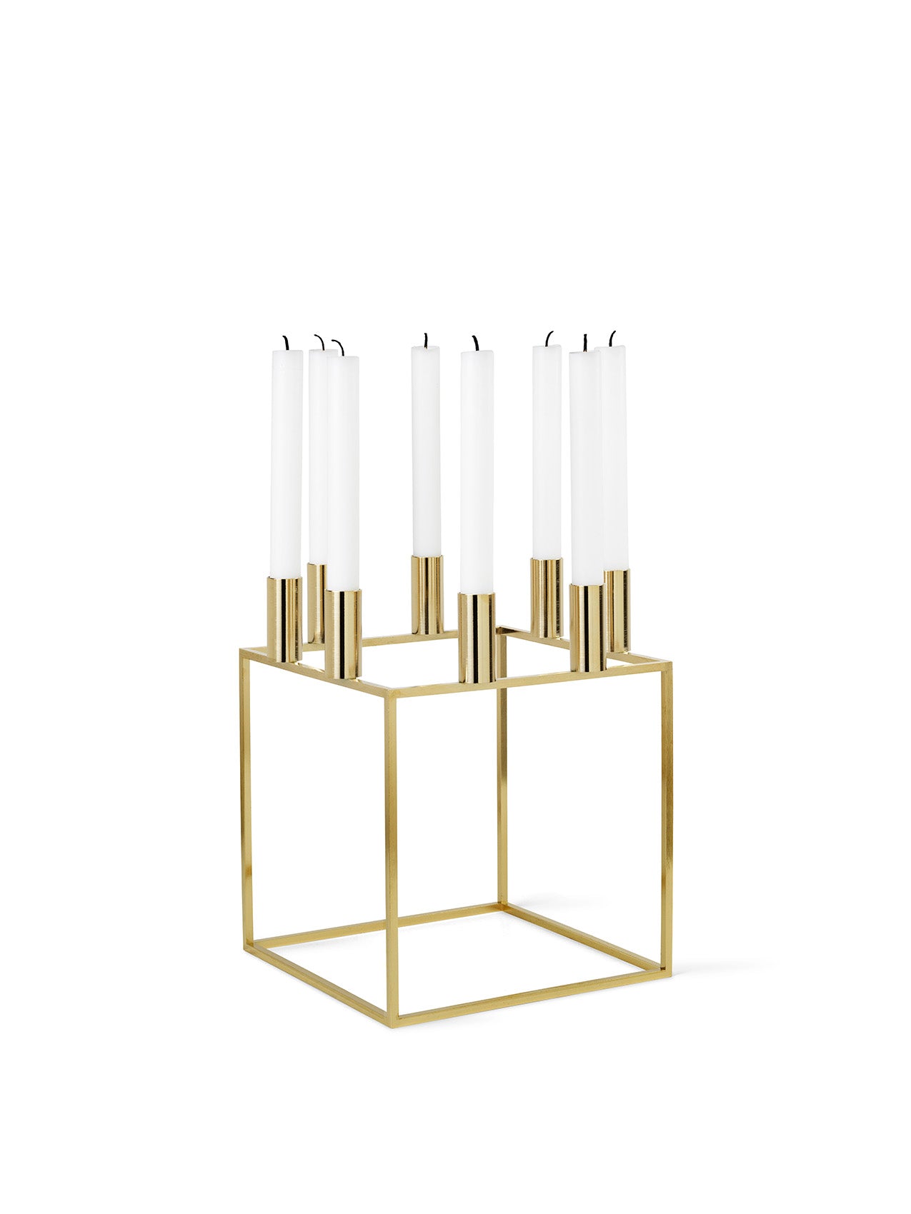 A gold-plated Kubus 8 candle holder with a geometric square base, holding eight tall, white taper candles.