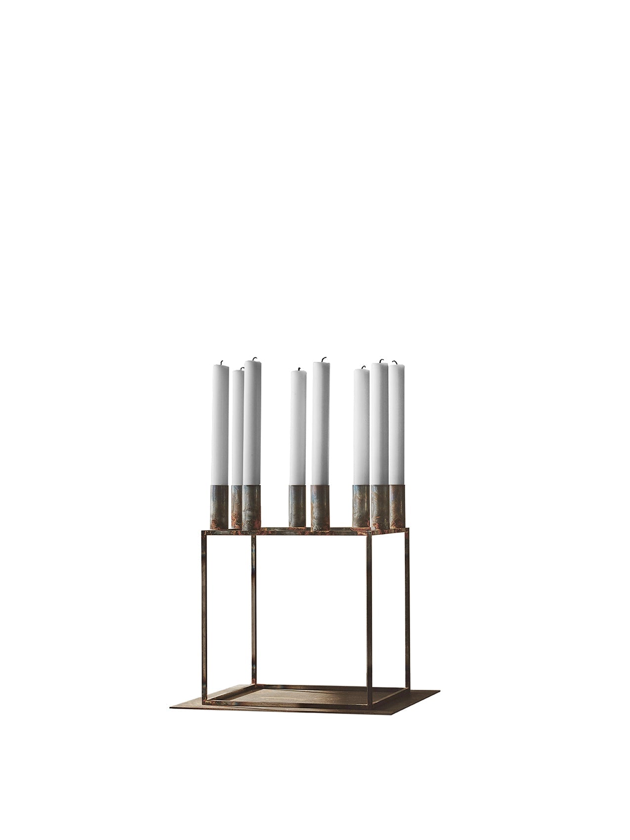 Front view of the Kubus 8 Raw candle holder, a geometric metal frame with weathered finish, holding eight tall white candles.