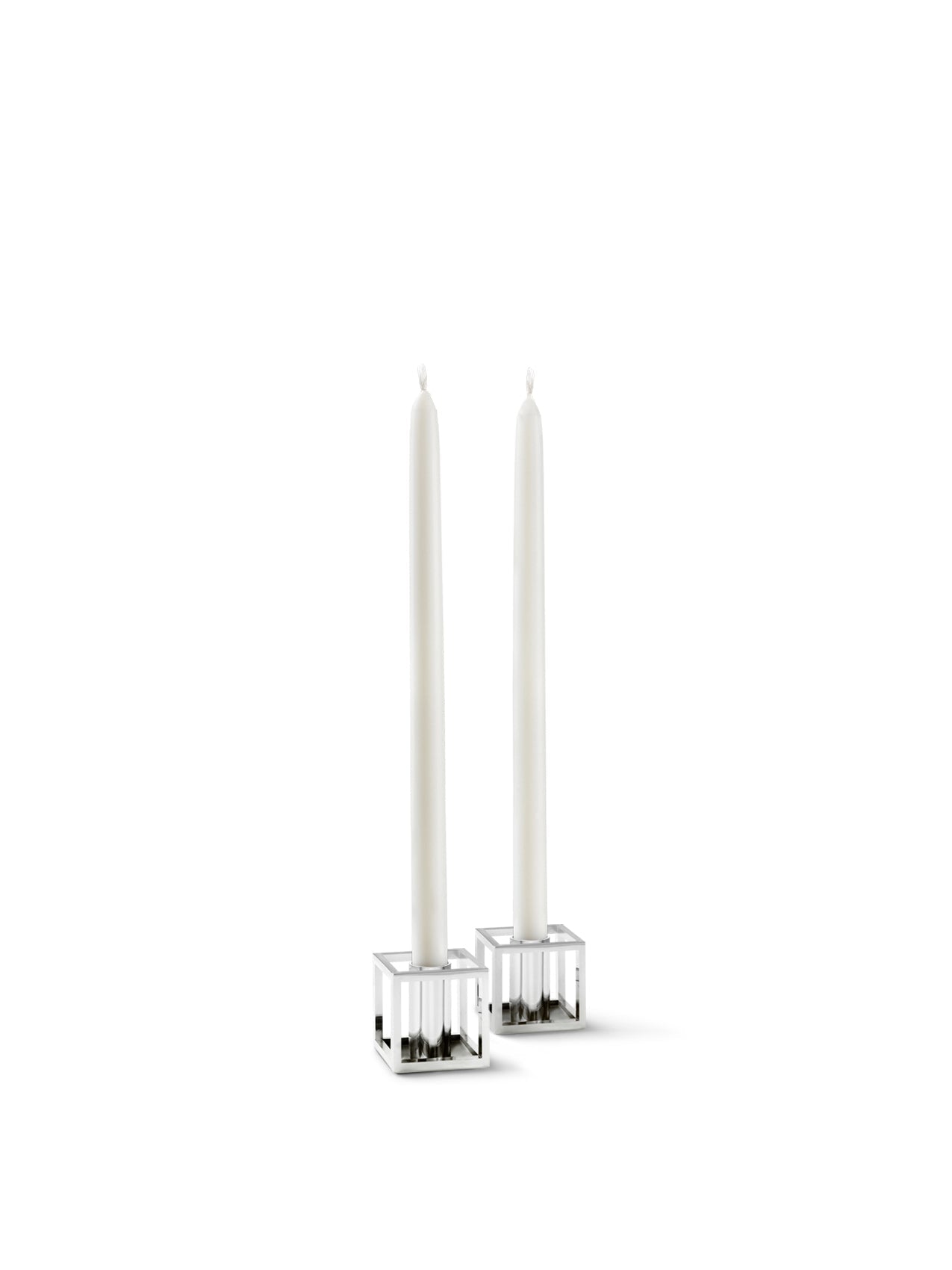 A pair of Kubus Micro candleholders in a polished nickel finish, each holding a tall, slender white taper candle.