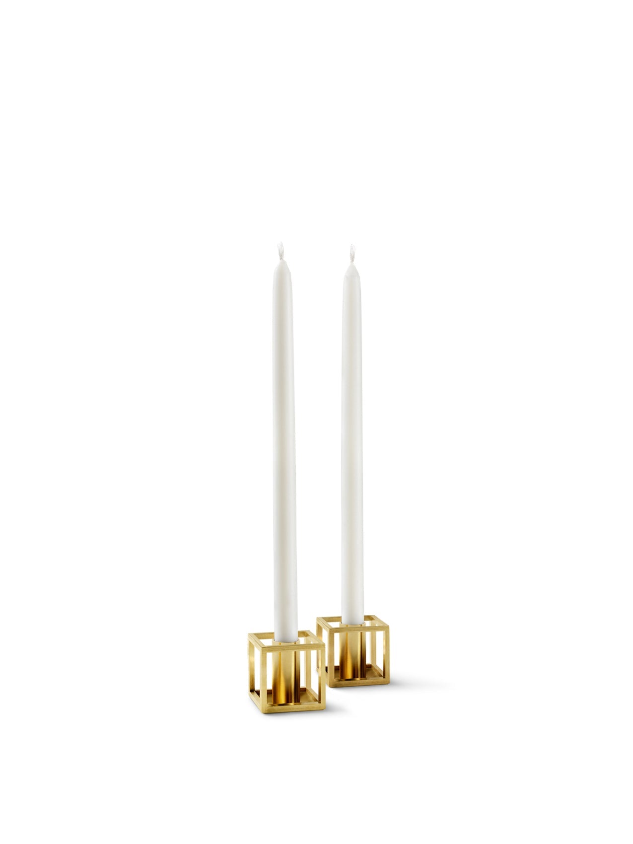 A pair of gold-plated Kubus Micro candle holders, each holding a tall, slender white candle against a plain white background.