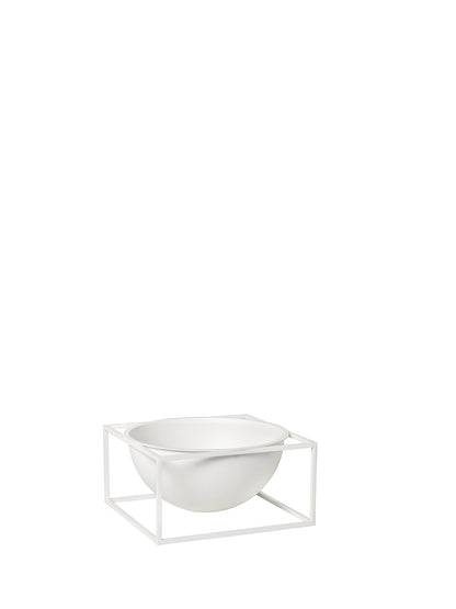 The large, white Kubus Bowl Centerpiece, a deep hemispherical bowl, rests within a square metal frame of the same colour.