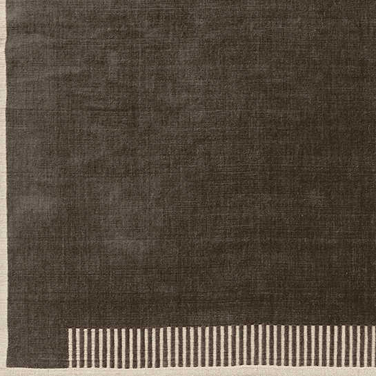 A close-up of the Duomo Rug in Marble Grey, showing the dark grey textured pile and the cream border with a striped pattern.