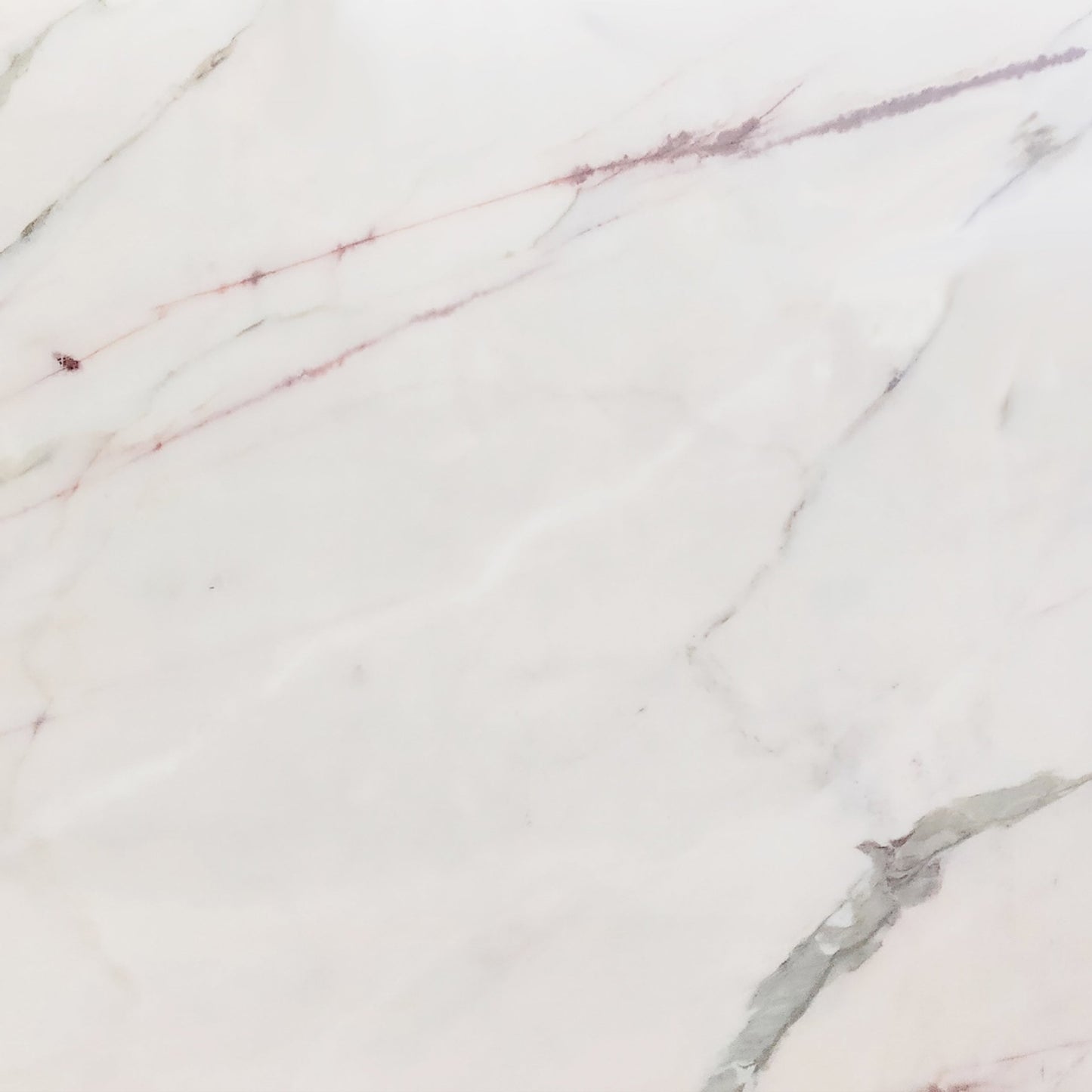 A close-up view of an Estremoz marble slab, showcasing its white base with delicate, diagonal veins of grey and mauve.
