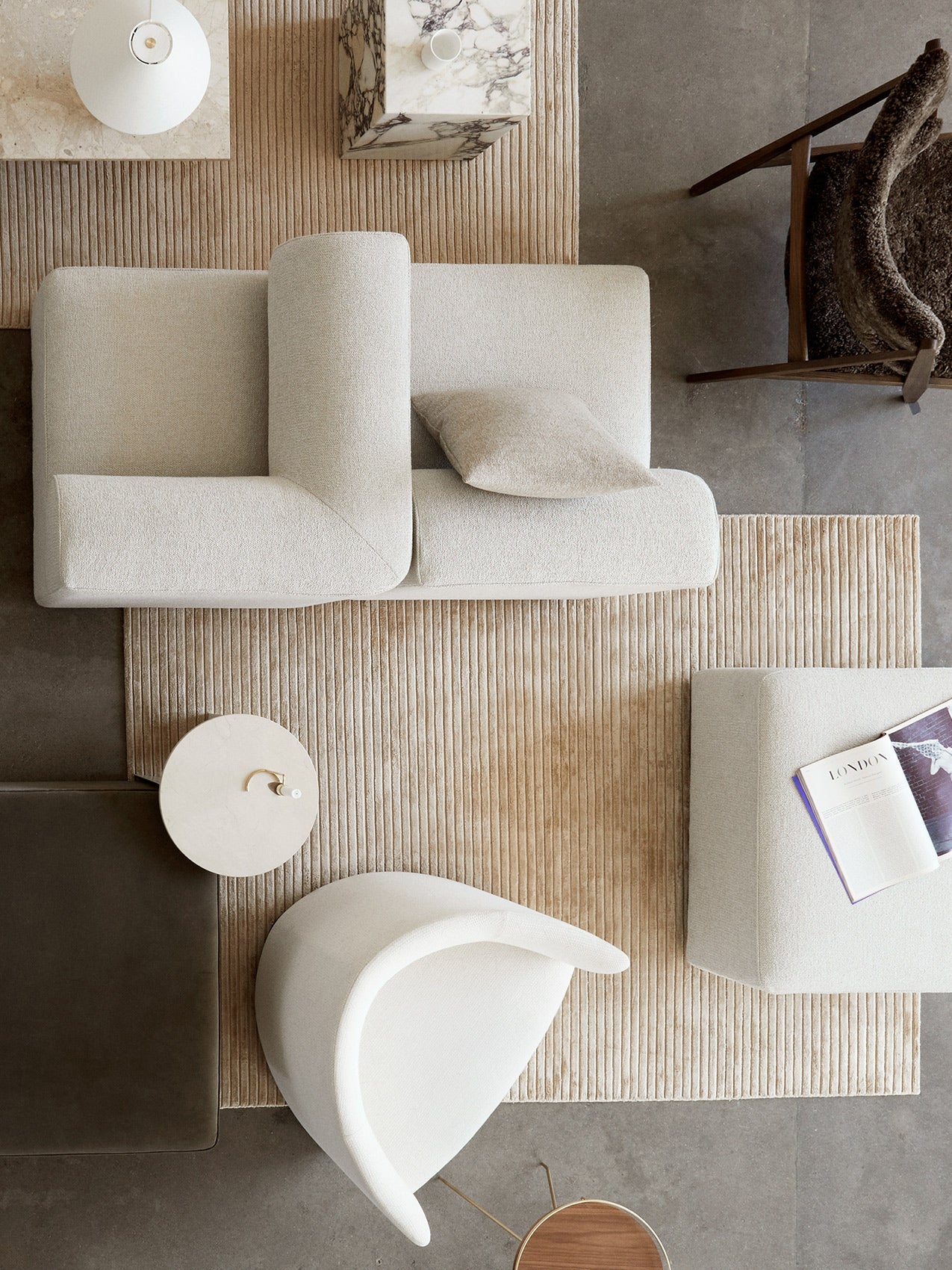 Top-down view of a living room featuring the cream Eave Modular Sofa and a beige, ribbed Houkime rug, with various chairs.