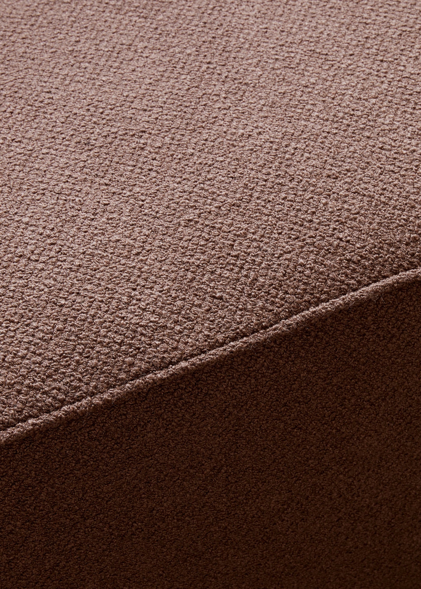 A close-up, detailed shot of the brown textured bouclé fabric on the Eave Modular Sofa, 96, Pouf, showing a corner seam.