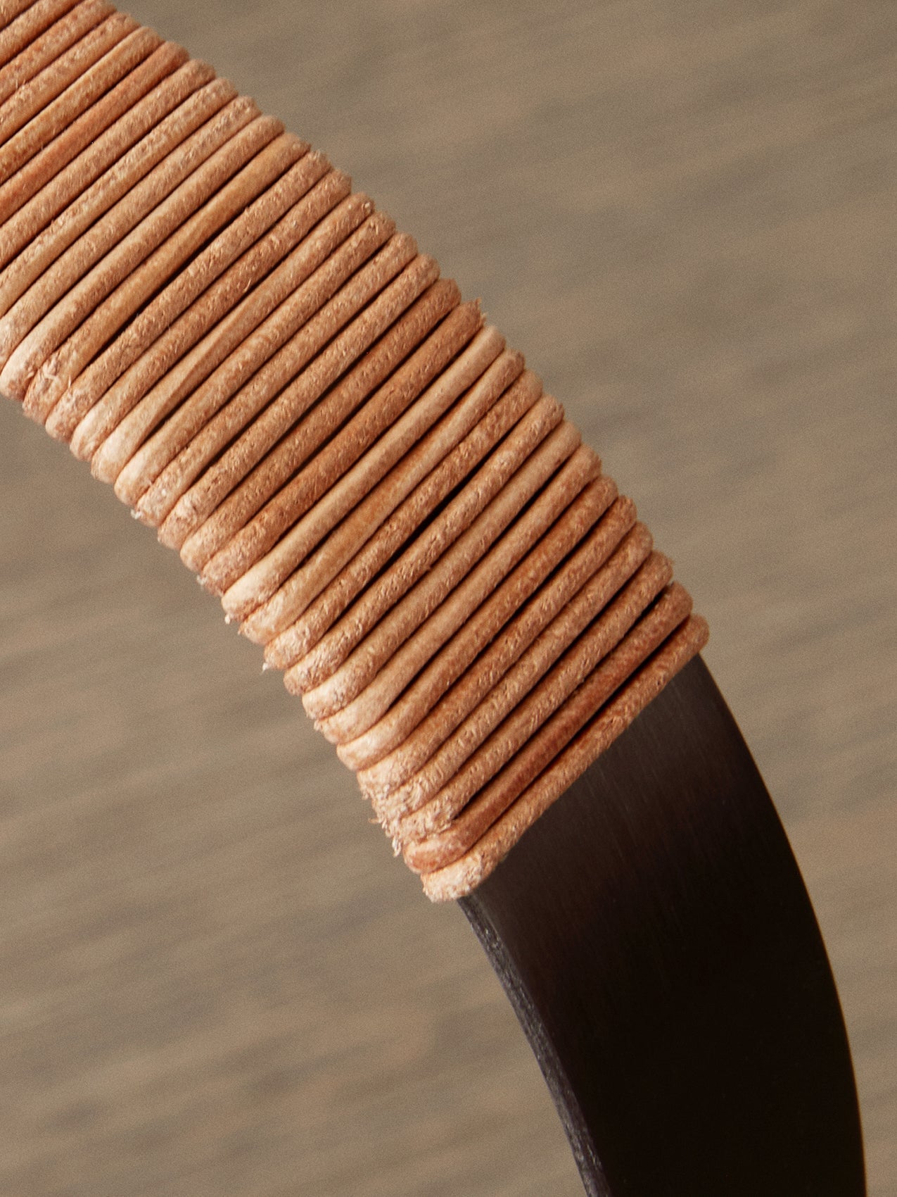 Close-up detail of the Carrie Table Lamp's handle, showing the light brown leather wrapping around the bronzed brass frame.