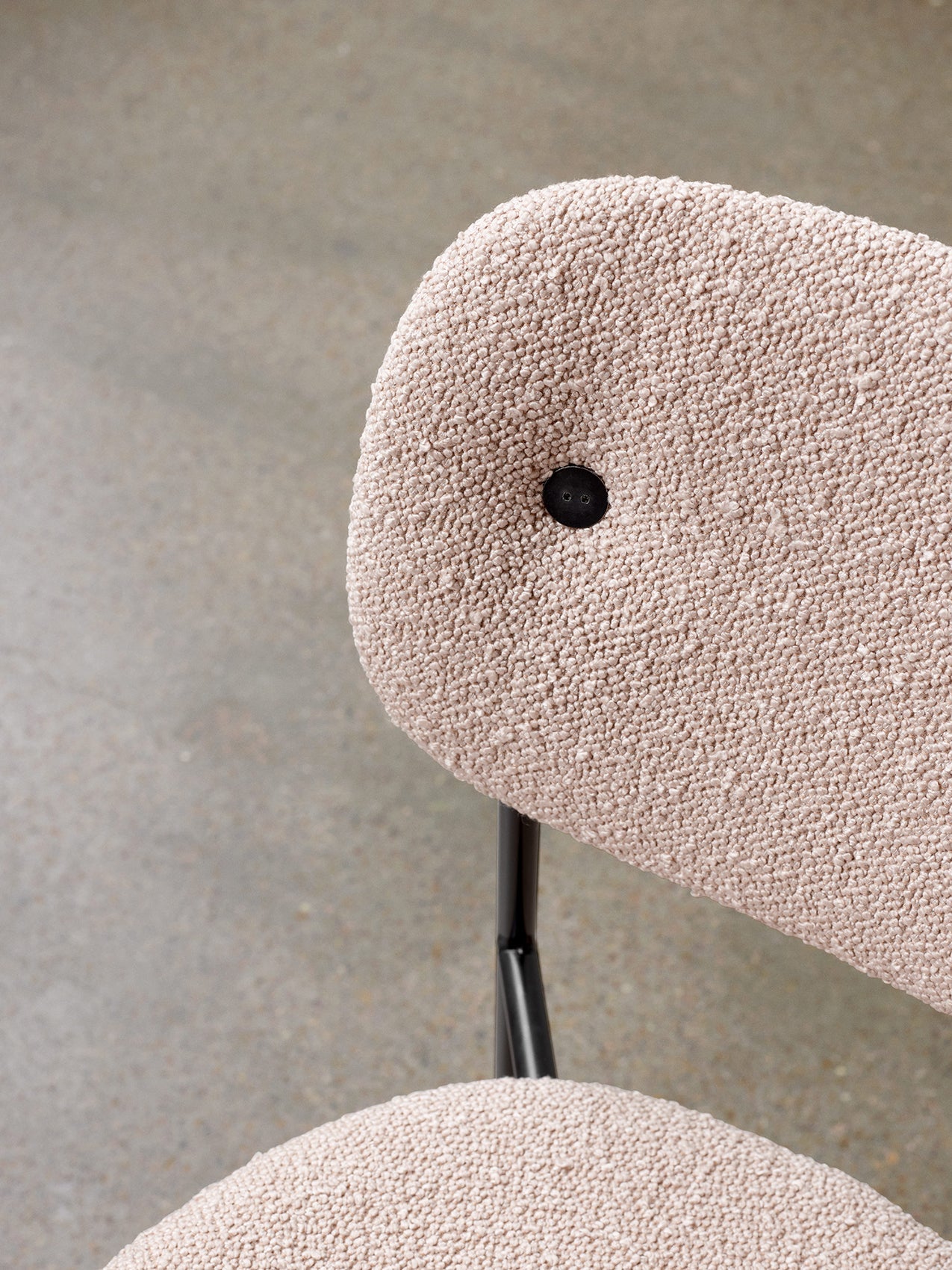 High-angle close-up of the Co Dining Chair, focusing on the textured, light-coloured bouclé upholstery of the backrest.