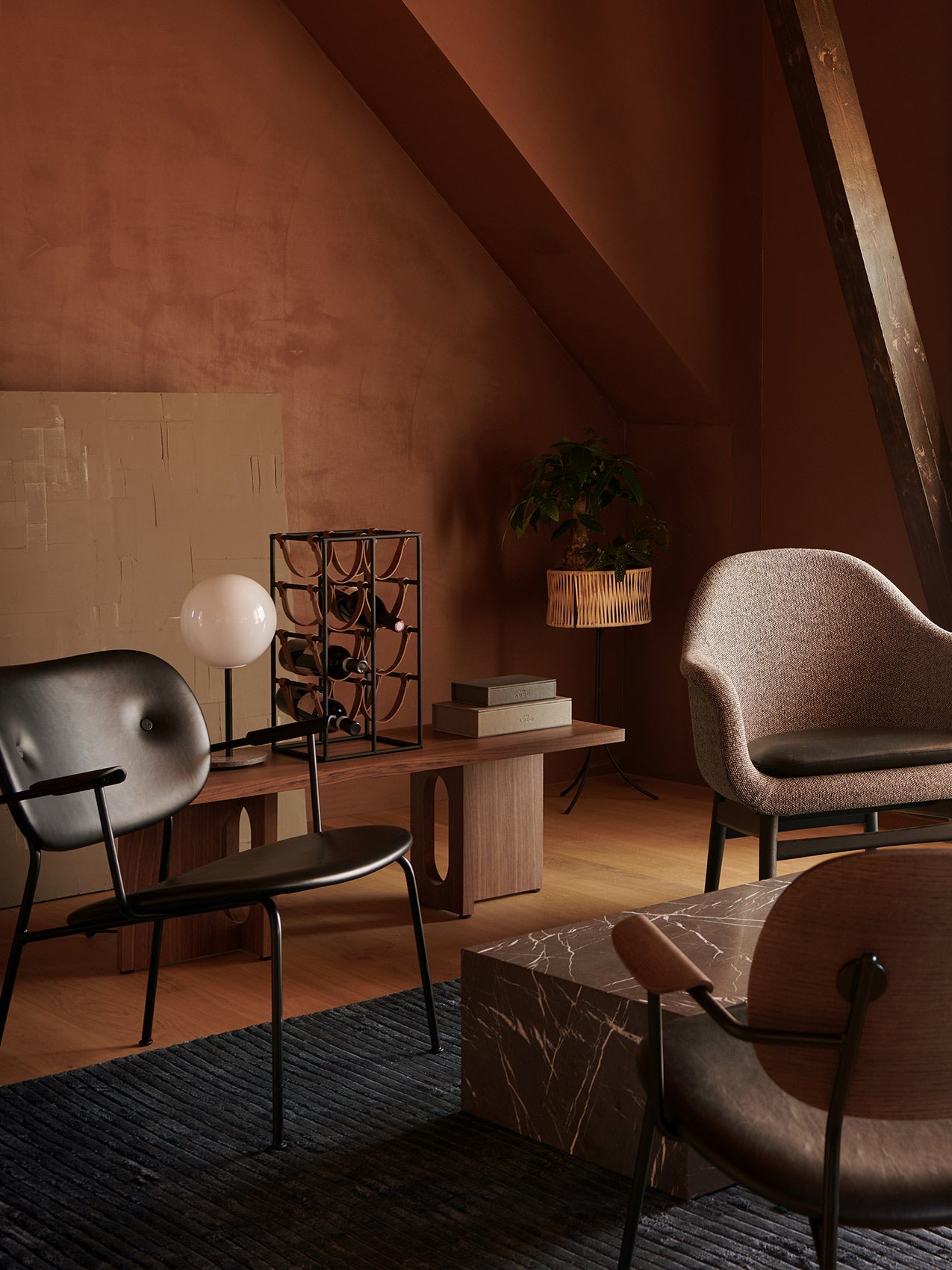 A fully upholstered Co Lounge Chair in a warmly lit, terracotta-toned room with a marble coffee table and wooden furniture.