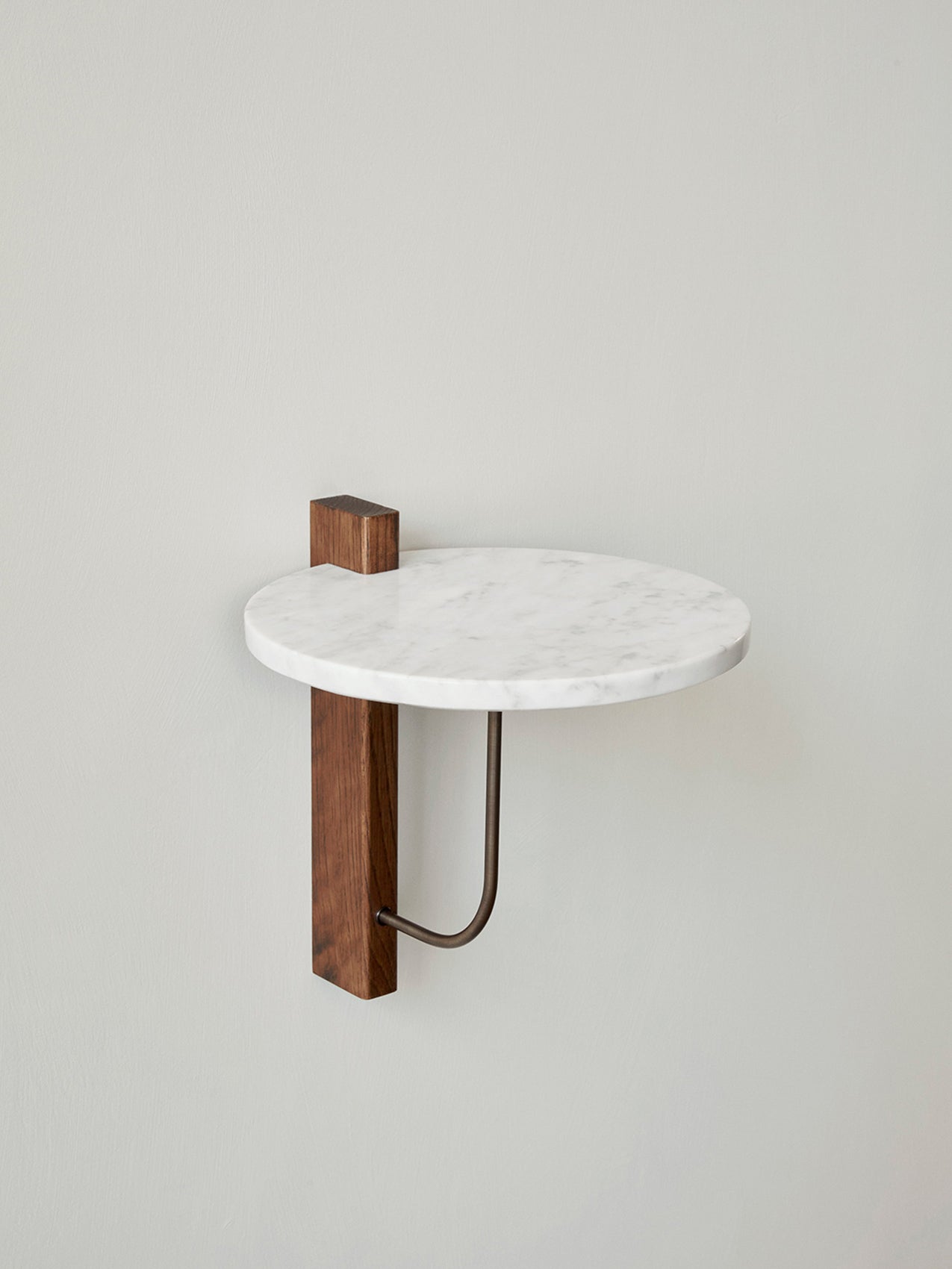 Side view of the Corbel Shelf, with a round white marble top, dark wooden wall mount, and dark metal bracket.