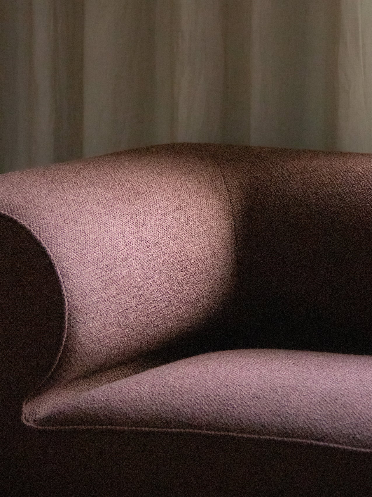 A detailed close-up of the Eave Modular Sofa's corner, highlighting the curved armrest and the texture of the mauve fabric.