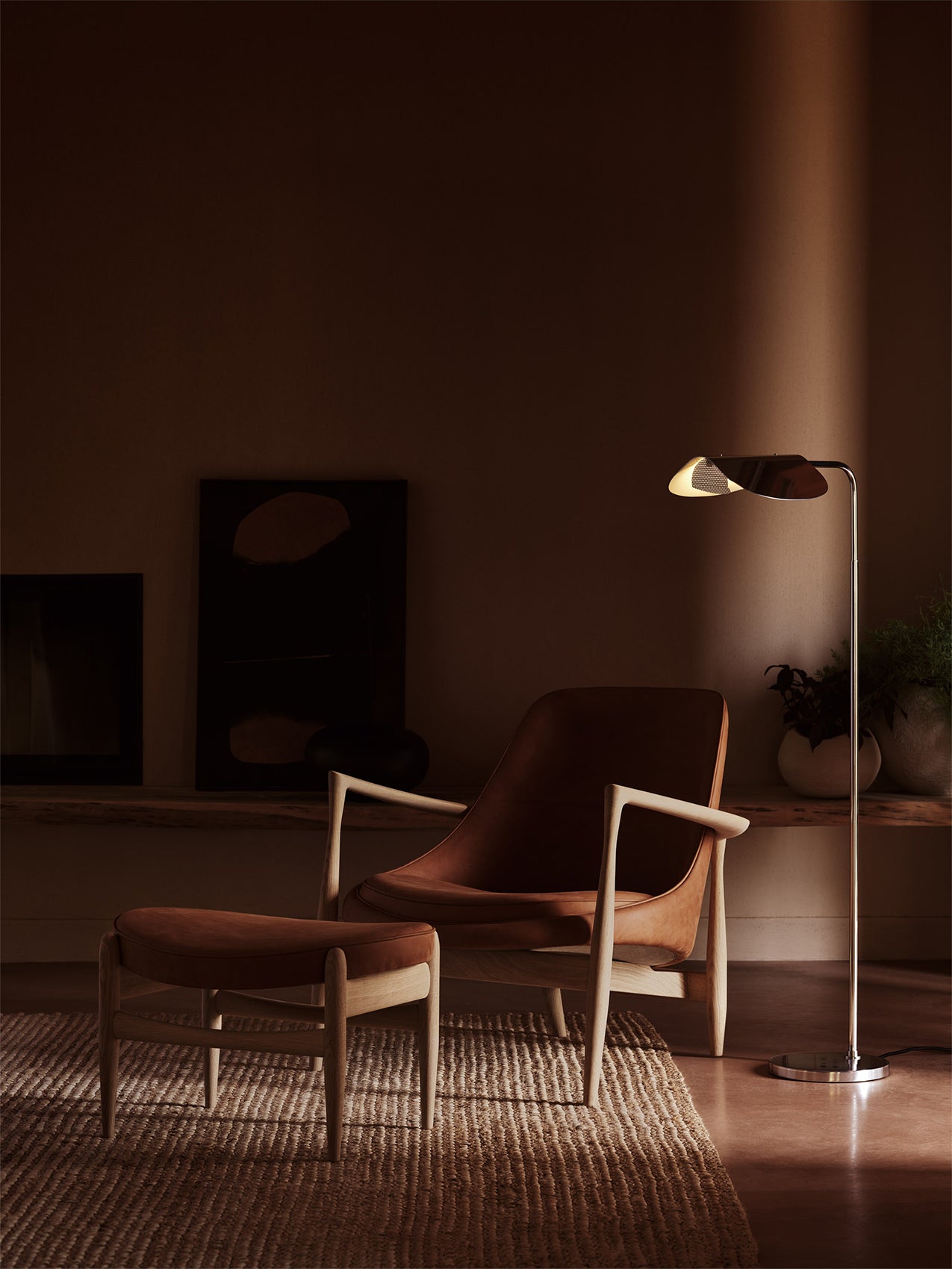 The Wing Floor Lamp in polished aluminium stands beside a brown leather Elizabeth Lounge Chair and ottoman in a warm room.