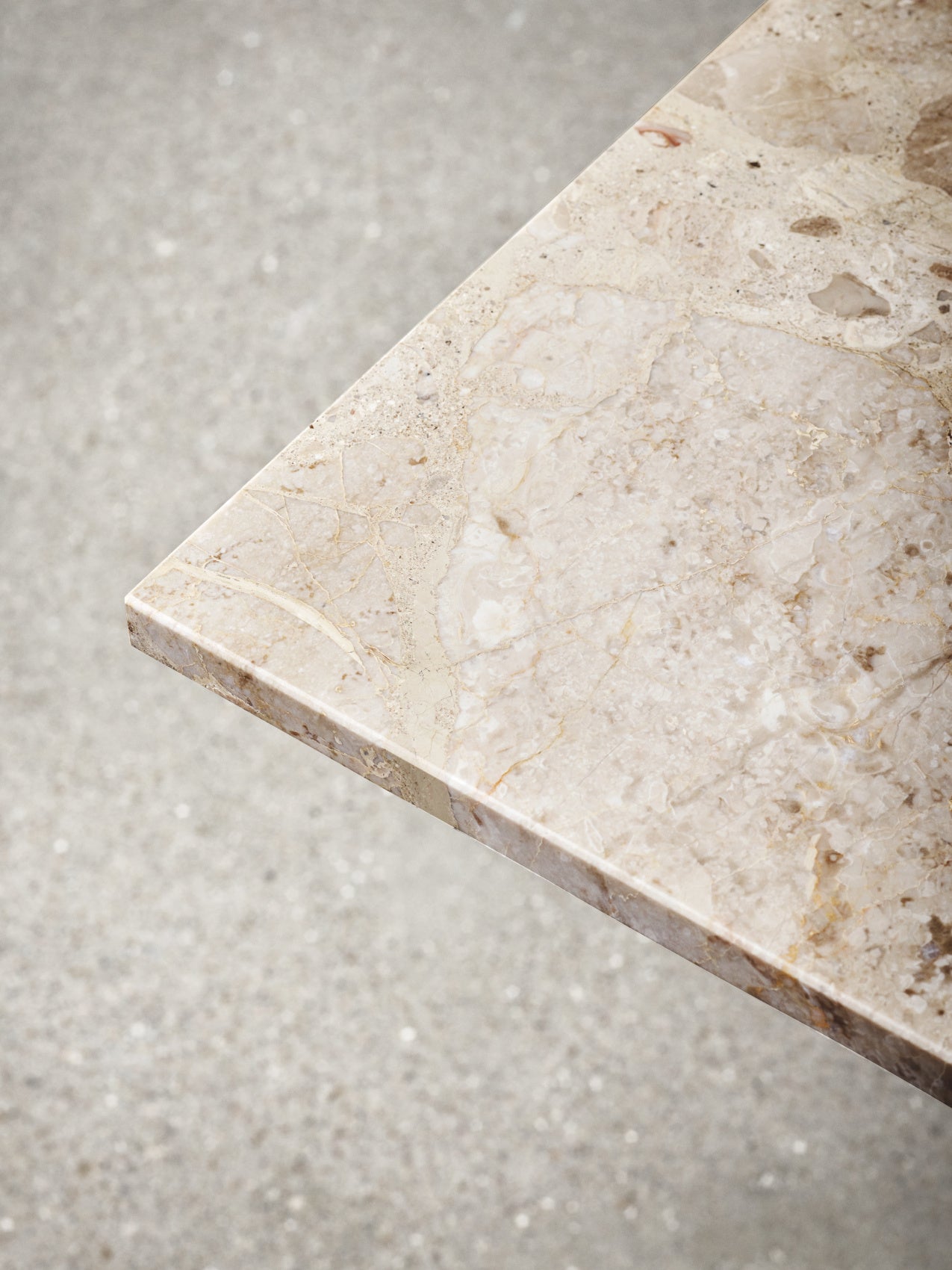 A detailed, top-down view of the Kunis Breccia marble corner of the Harbour Column Table, showcasing its rich, earthy tones.