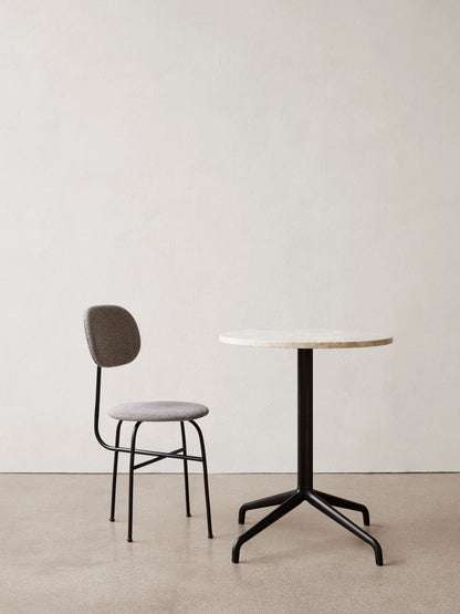 A grey patterned Afteroom Dining Chair Plus with black frame stands next to a Harbour Column Dining Table with a marble top.