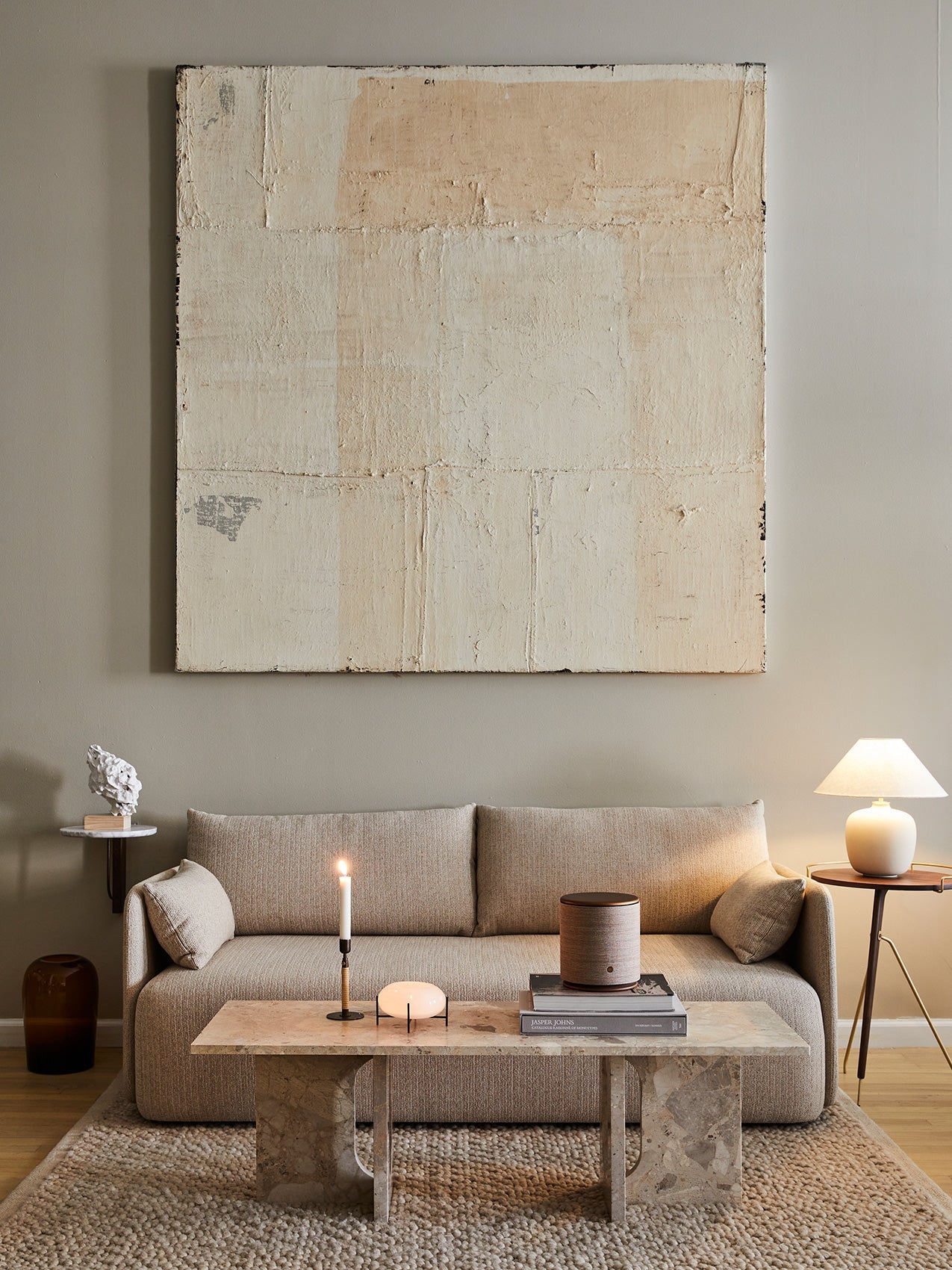 A living room with a beige Offset Sofa, a marble Androgyne Lounge Table, and a large abstract painting on the wall.