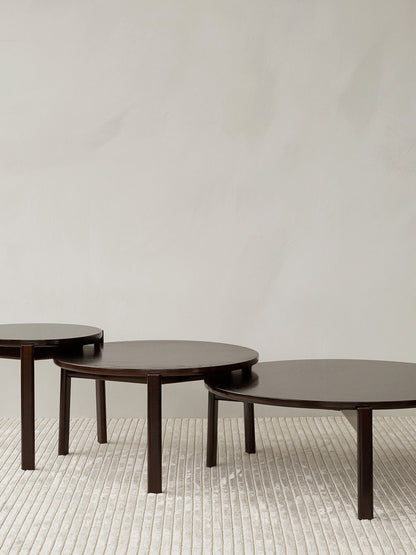 Three dark wood Passage Lounge Tables of different sizes arranged in a nesting formation on a light grey Houkime rug.