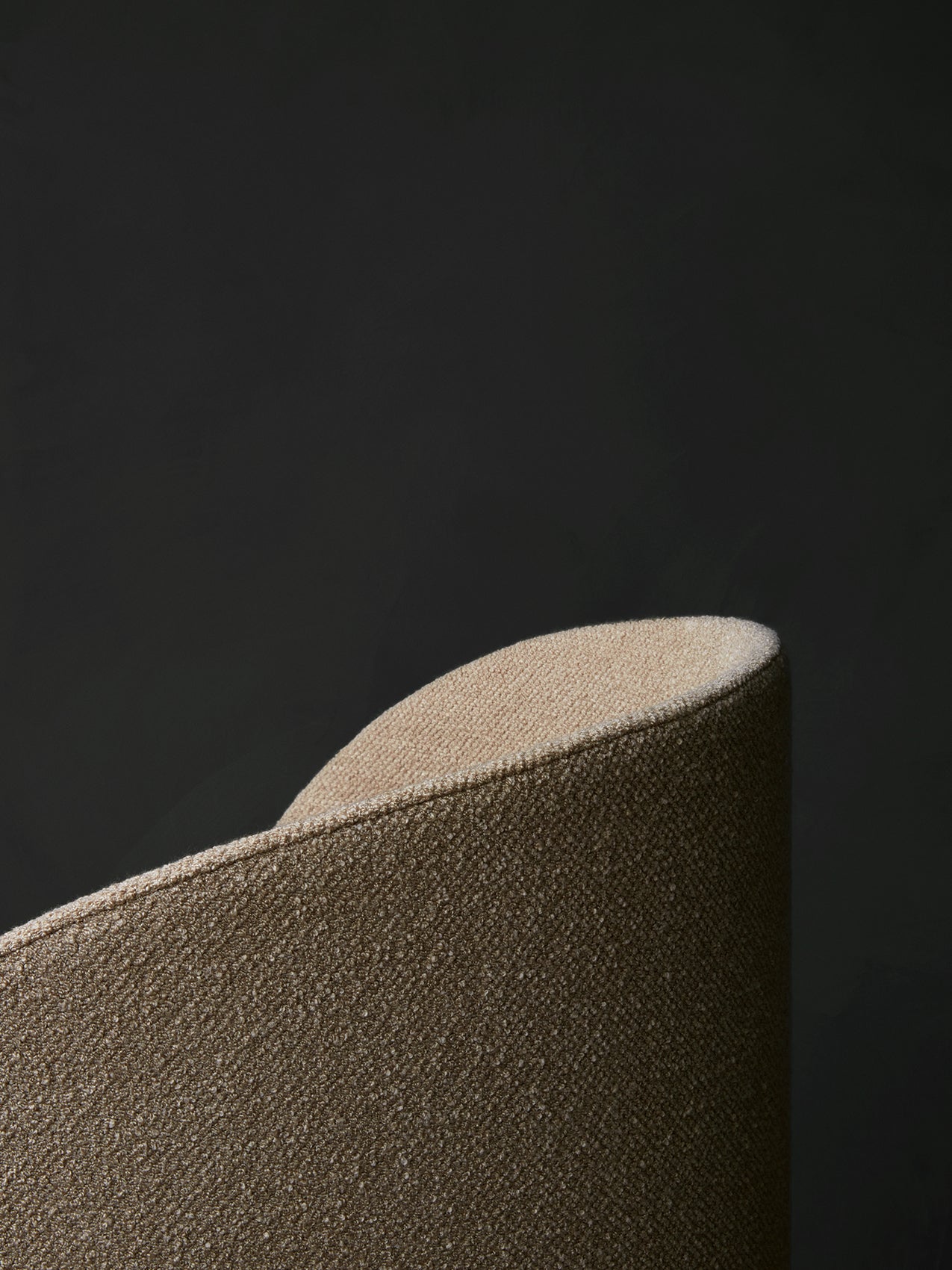 A close-up of the Tearoom Lounge Chair, High Back, showing the textured light brown upholstery on its curved top corner.