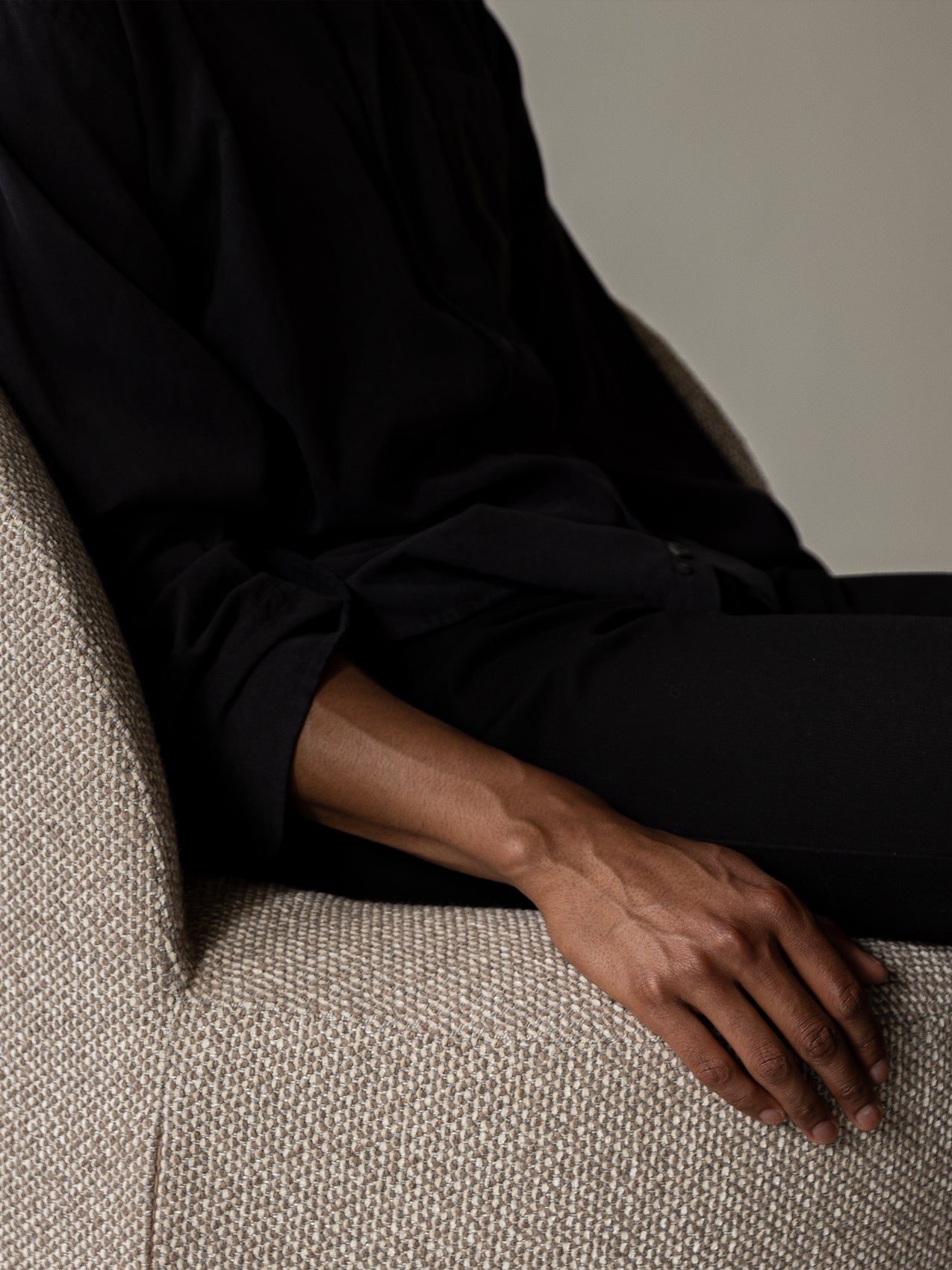 Close-up of the Tearoom Lounge Chair showing the detailed texture of the fabric upholstery with a person's arm resting on it.