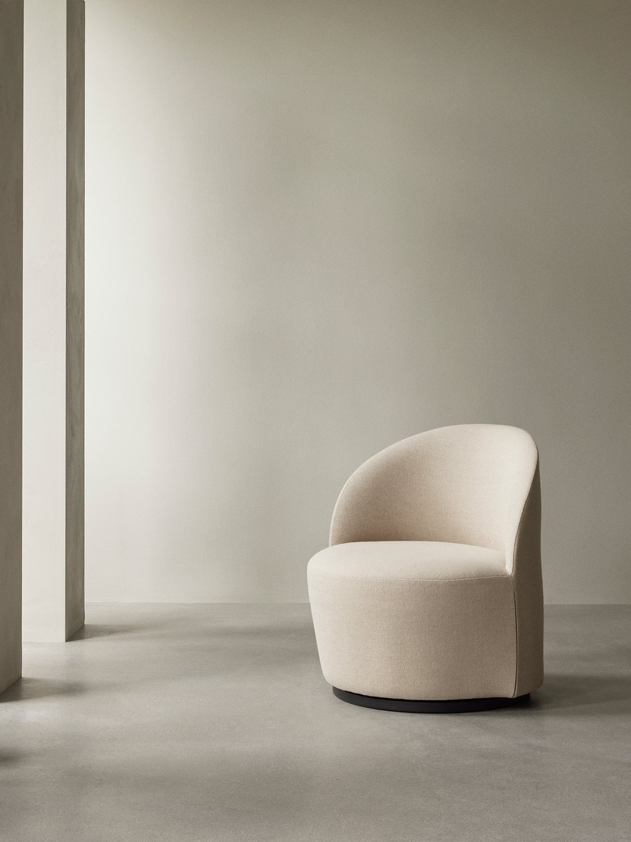 The cream bouclé Tearoom Lounge Chair, Swivel w/Return, sits in a minimalist room with a concrete floor and soft lighting.