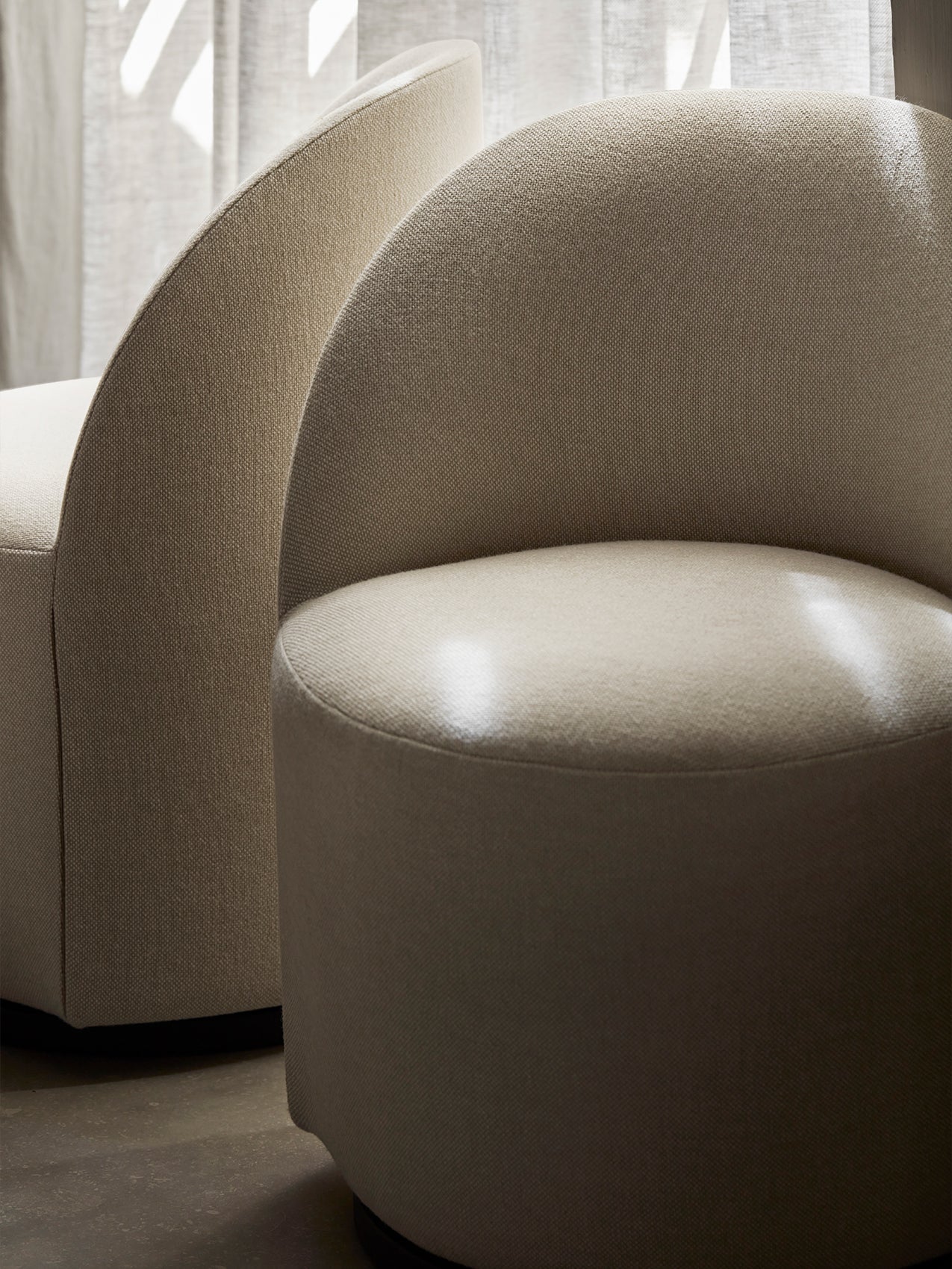 A close-up of two beige Tearoom Club Chairs, Swivel w/ Return, highlighting the curved backrest and textured upholstery.