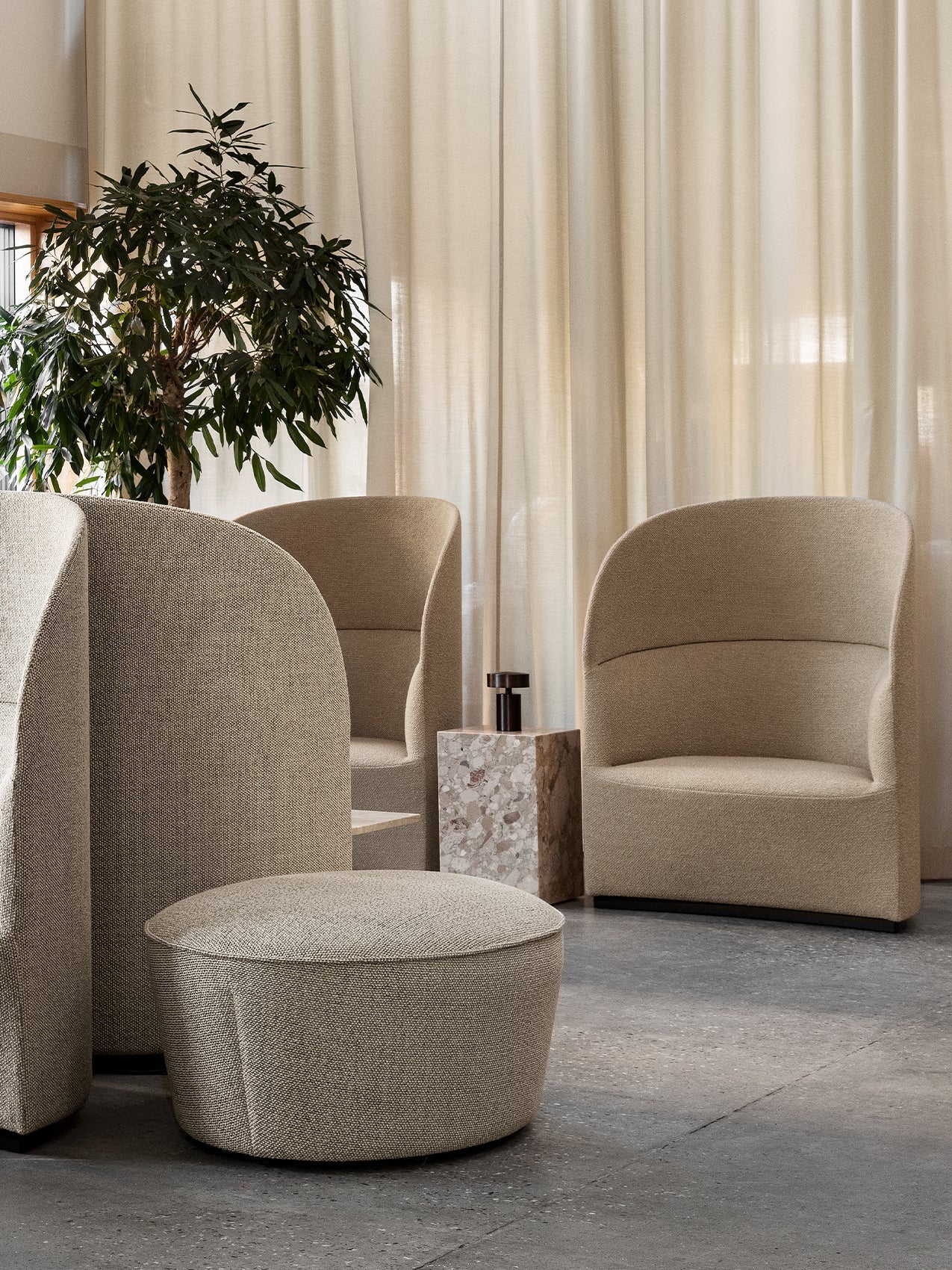 Beige Tearoom high-back sofas and chairs with a Cairn pouf and Plinth Cubic side table arranged in a modern interior.