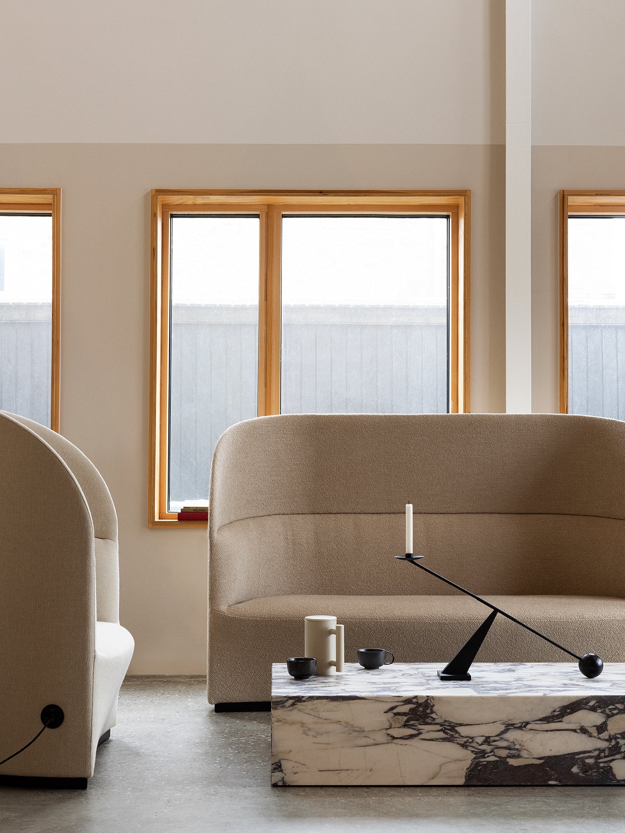 A beige Tearoom Sofa, High Back, and Lounge Chair with a marble Plinth table and a Grand Interconnect Candle Holder.