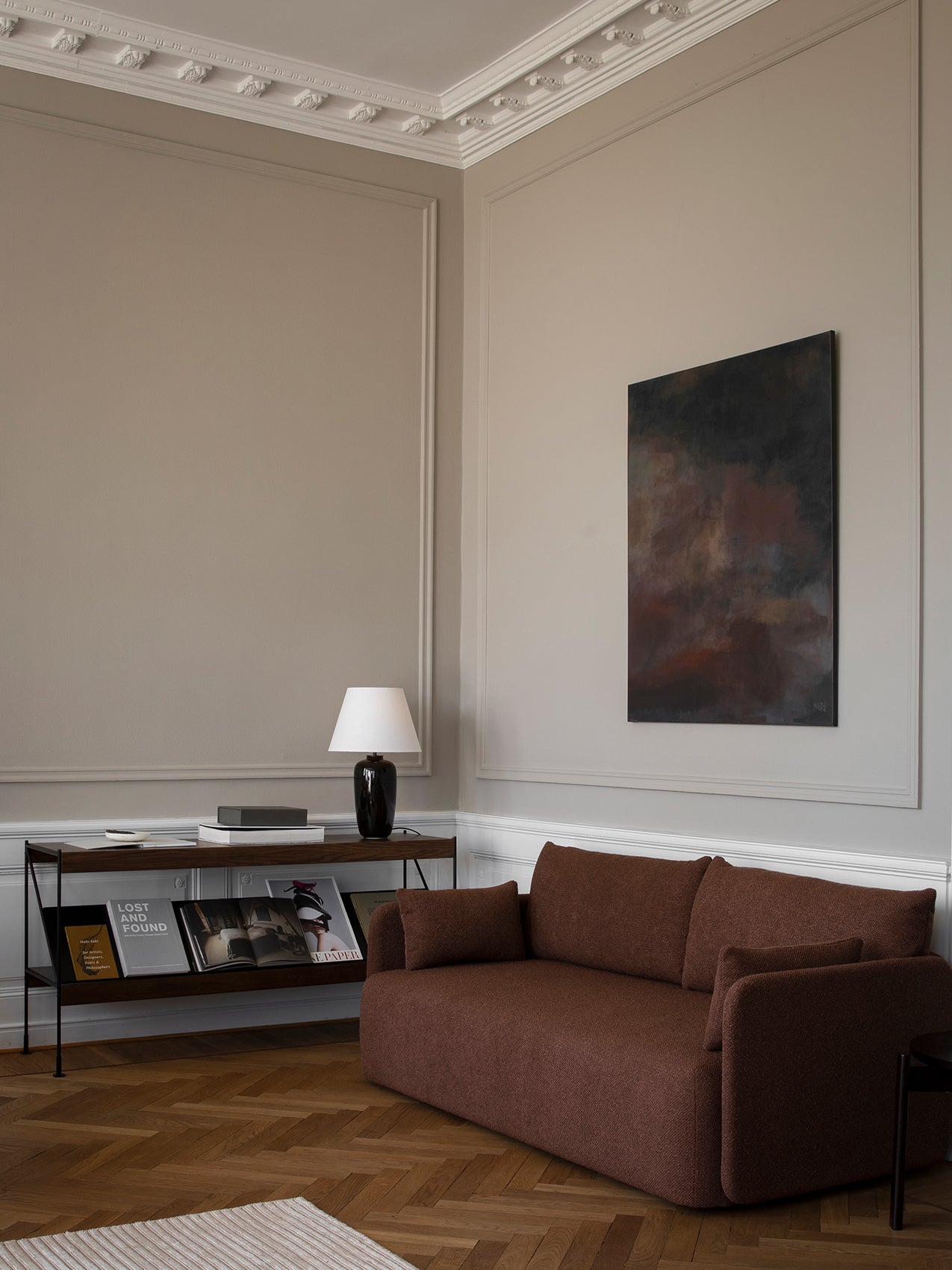 Brown Offset Sofa in a classic living room with grey walls, herringbone floor, a console table and abstract art.