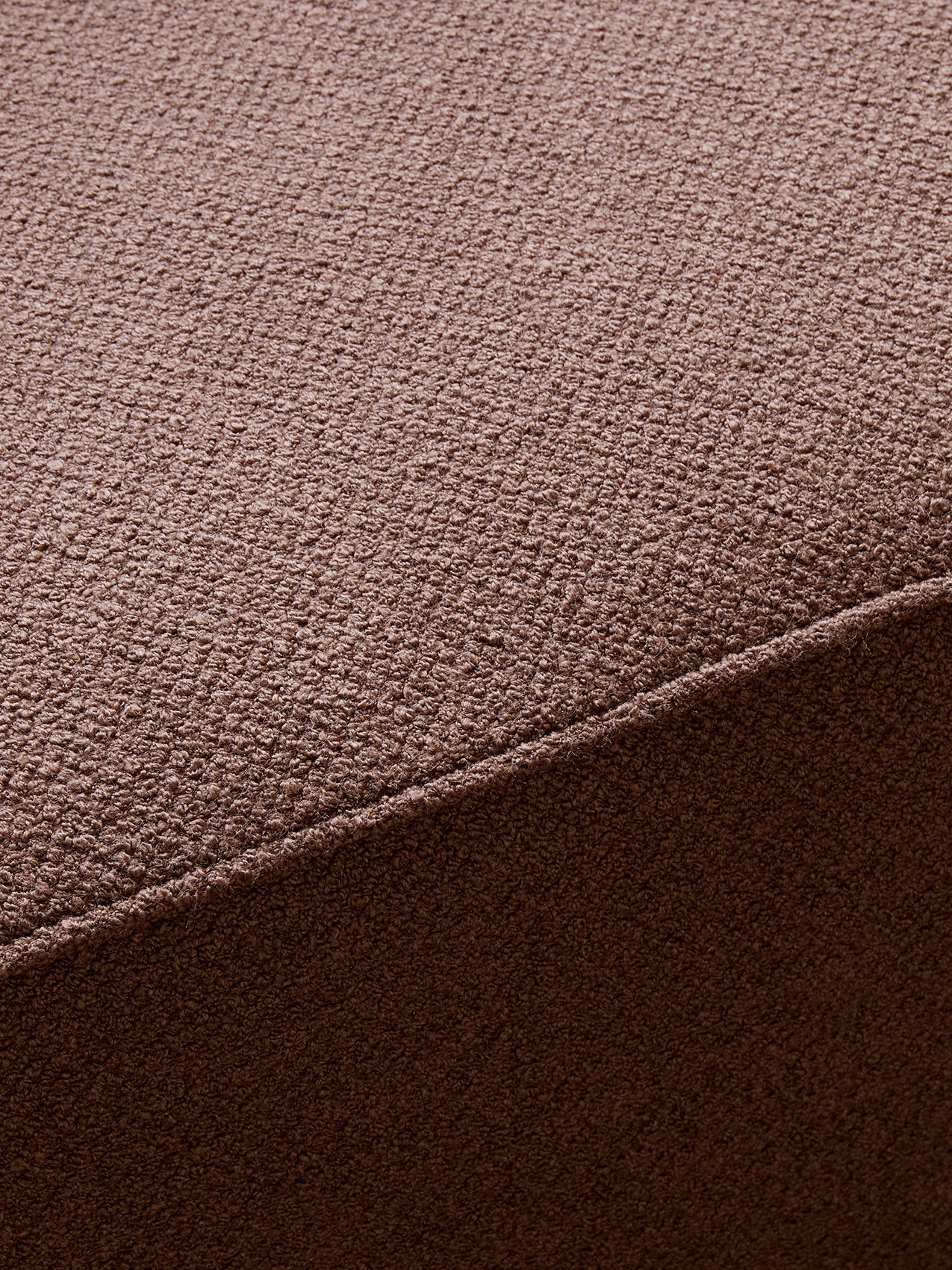 A close-up of the Eave Modular Sofa, detailing the texture and weave of its brown bouclé fabric upholstery and a neat seam.