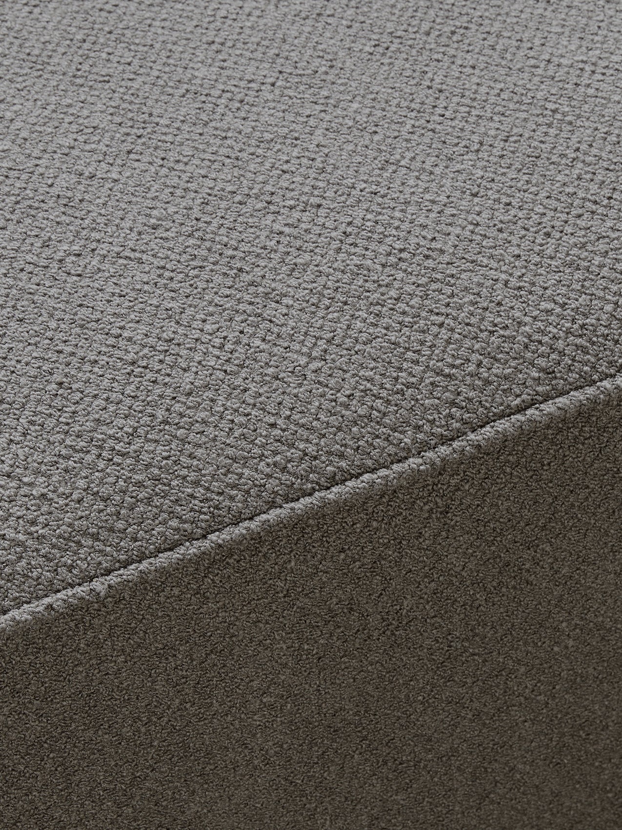 A close-up, detailed shot of the textured grey fabric on the Eave Modular Sofa, showing a diagonal seam across a corner.
