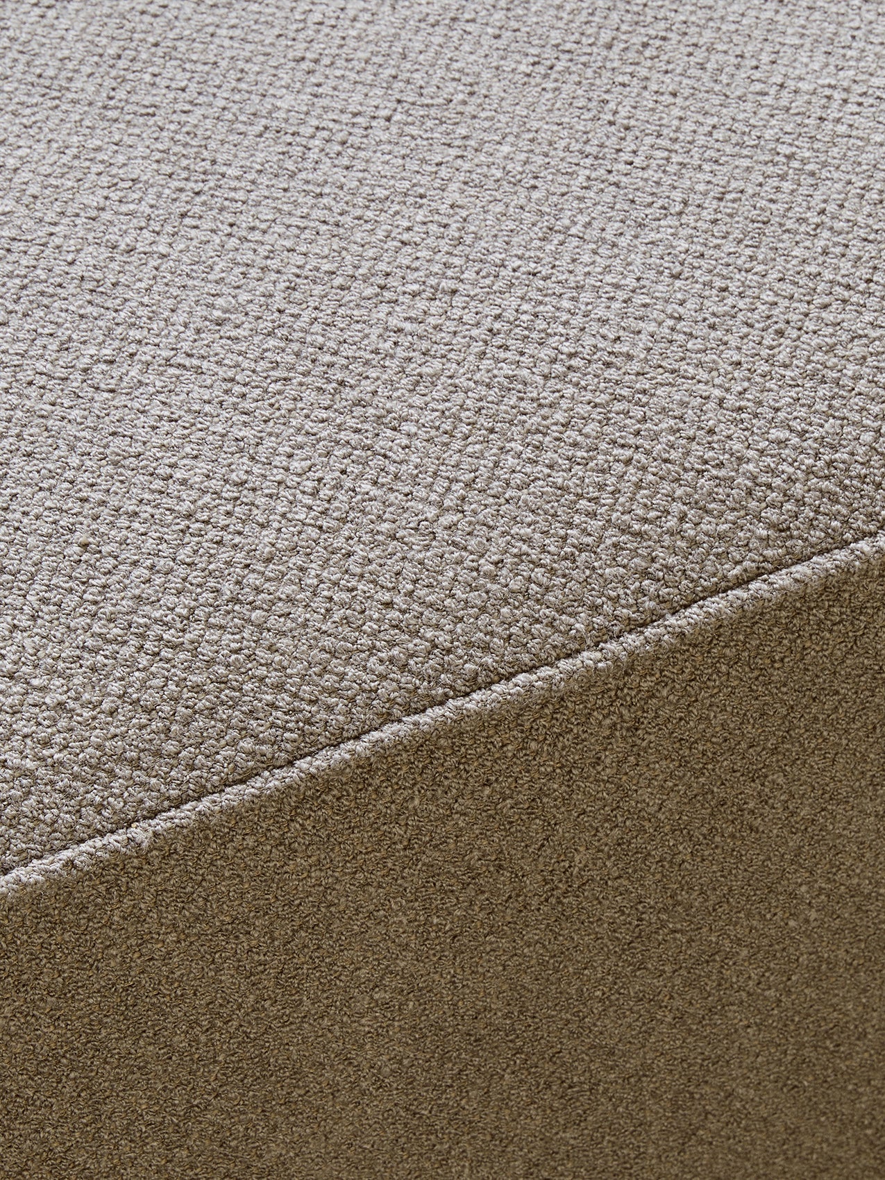 A close-up detail shot of the Eave Modular Sofa's textured, light beige bouclé upholstery, with a prominent diagonal seam.