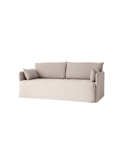 Angled view of the Offset Sofa w. Loose Cover in a light grey fabric, with two large back and two smaller side cushions.
