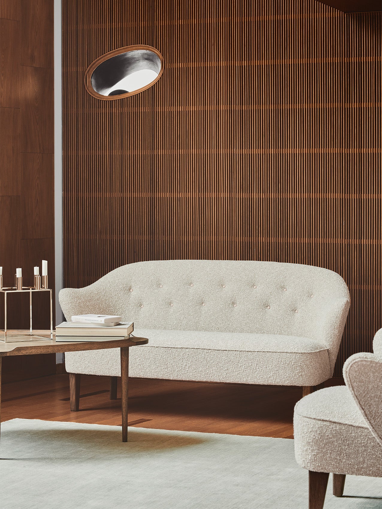 A cream Ingeborg Sofa and matching lounge chair in a room with a slatted wood wall, next to a coffee table with a Kubus 8.