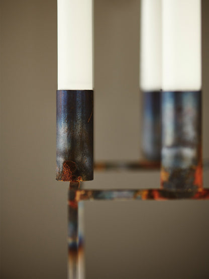 Close-up of the raw, patinated metal finish on the byLassen Kubus 8 candlestick, holding a simple white candle.