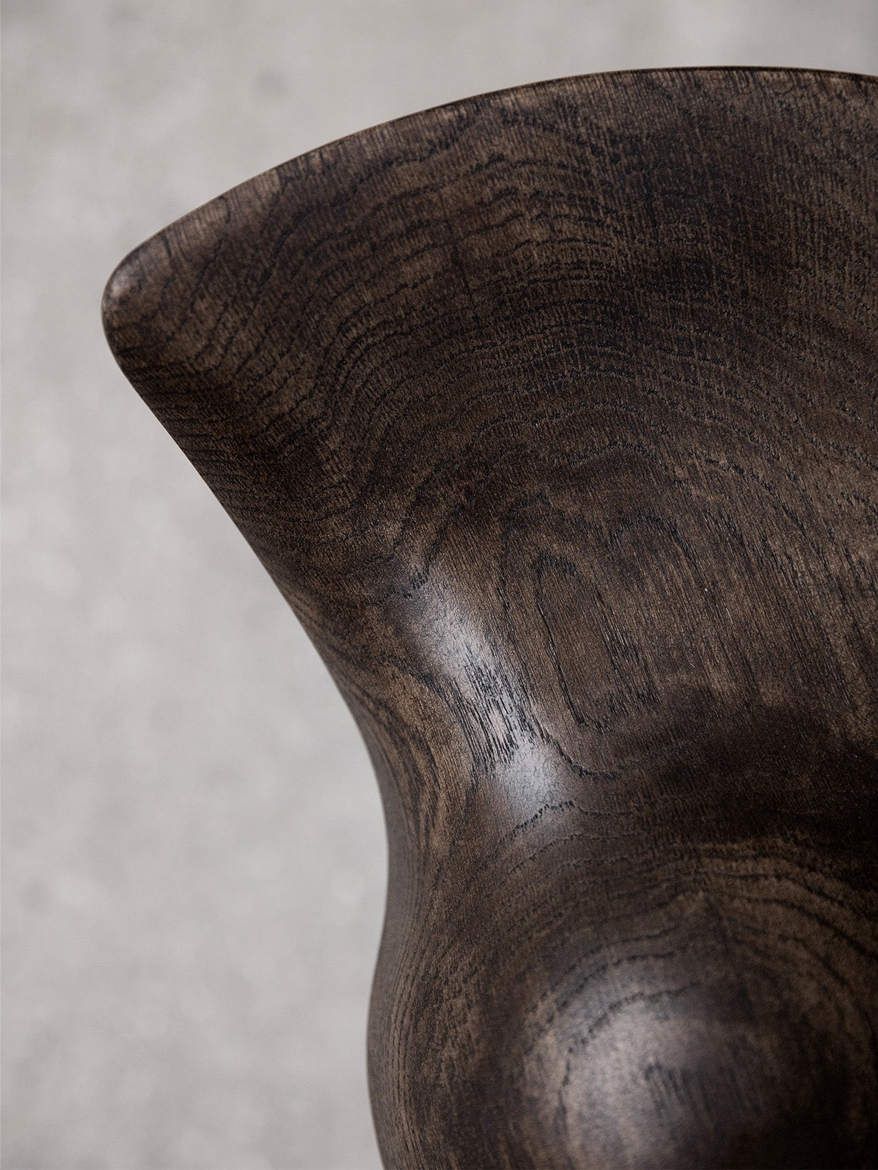A close-up, detailed shot of the ML 42 Bar Stool's seat, showing the rich, dark grain and sculptural curves of the wood.