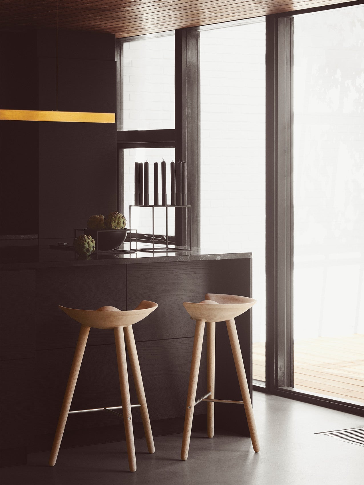 Two ML42 Counter Stools in a modern kitchen. On the counter is a Kubus 8 candle holder and a Kubus Bowl with artichokes.
