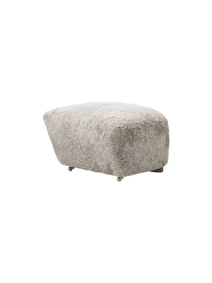 Three-quarter view of The Tired Man Ottoman in plush Green Tea Sheepskin, highlighting its soft texture on a black background