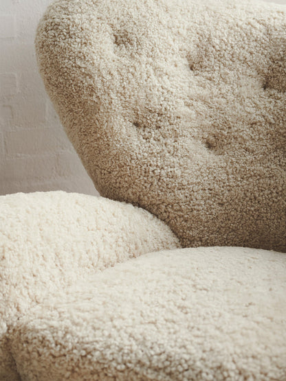 Close-up of The Tired Man Lounge Chair's plush, off-white sheepskin upholstery, detailing the tufted backrest and soft seat.