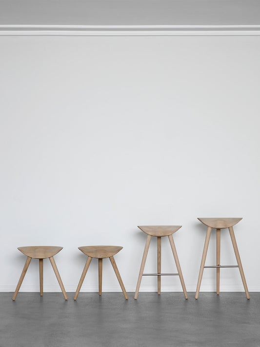 A row of four ML 42 stools in light oak, showcasing the different heights from stool to counter and bar stool versions.