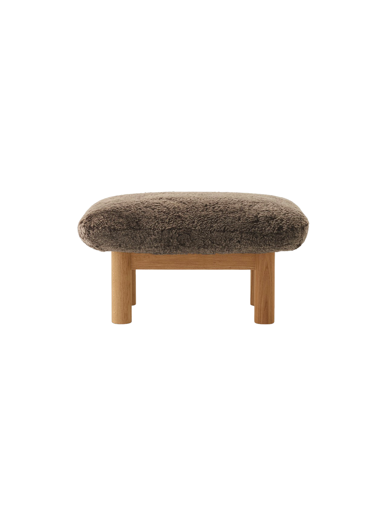A front view of the Brasilia Ottoman, featuring a plush, brown sheepskin cushion atop a natural oak frame with robust legs.
